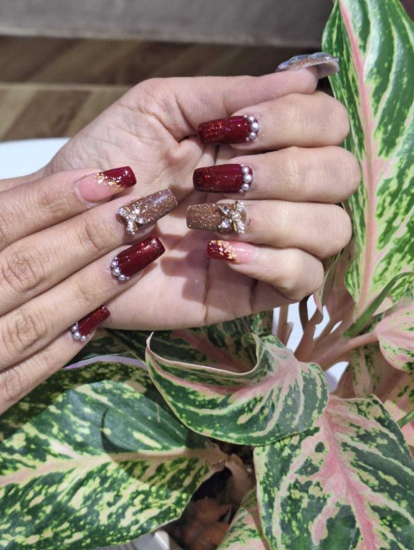 Maroon and glitter nail art with embellishments